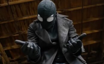 closeup of a man in black spiderman suit holding both hands out in front of him, ready to fire out webbing