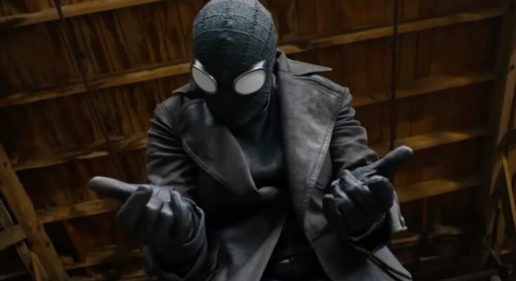 closeup of a man in black spiderman suit holding both hands out in front of him, ready to fire out webbing