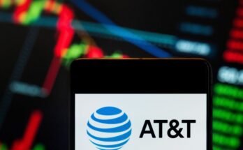 AT&T logo displayed on a smartphone with a stock exchange index graph in the background.