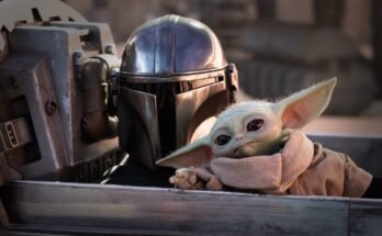 mandolorian in full armor and helmet with little green yoda-like figure sitting in a spacecraft