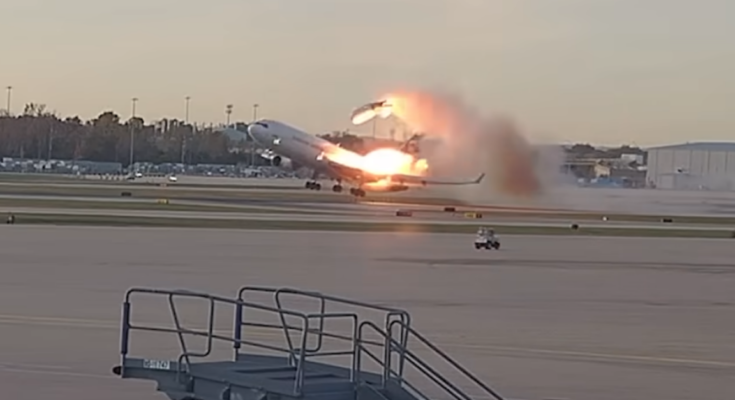 Still image from a video showing a cargo plane taking off while fire engulfs a wing and the left engine having detached. The crash of UPS flight 2976 killed three pilots aboard the aircraft and killed a dozen more people on the ground, with 23 people being injured.