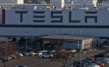 Aerial view of a Tesla factory showing the parking lot and exterior