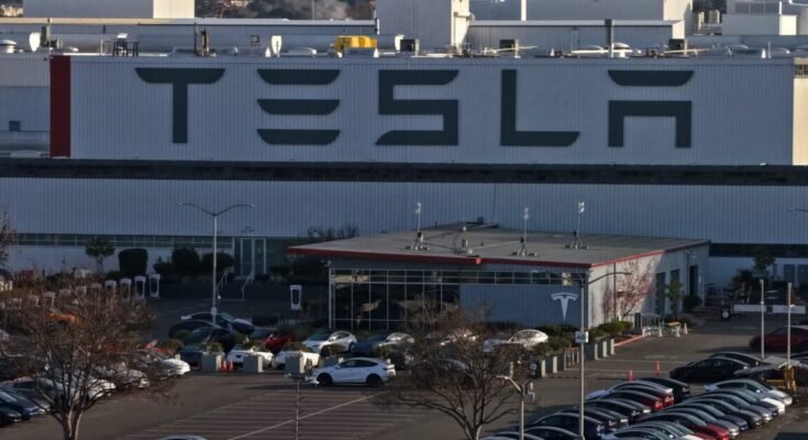 Aerial view of a Tesla factory showing the parking lot and exterior