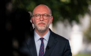 Image of a white man in a suit with glasses.