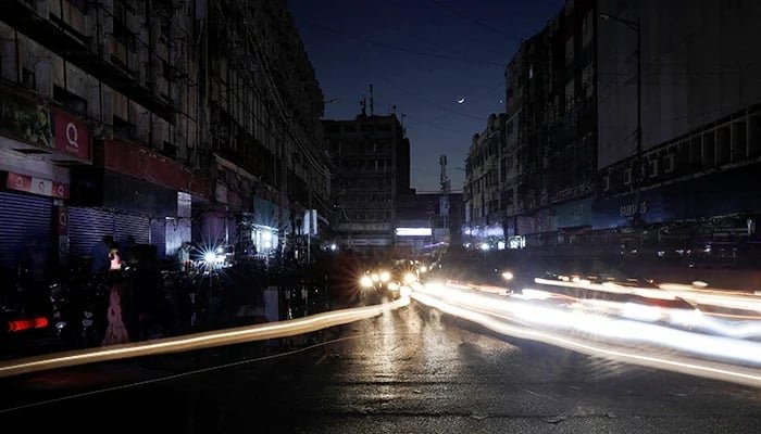 23 جنوری 2023 کو کراچی میں ملک بھر میں بجلی کے بریک ڈاؤن کے دوران ایک شخص اپنی دکان کے باہر بیٹھا ہے۔ - رائٹرز