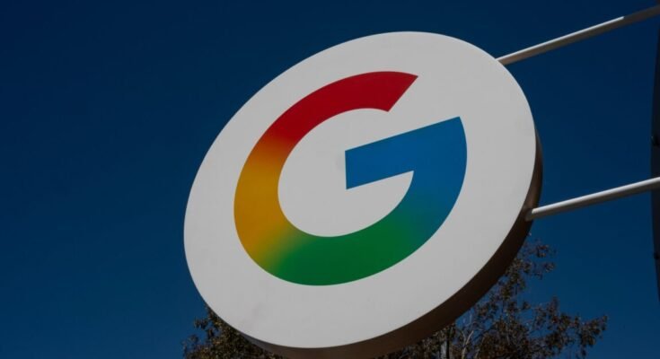 A large sign with Google's "G" logo hangs outside during the daytime.