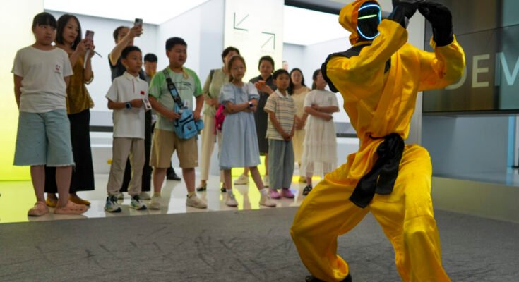 Children watch a martial arts performance by Unitree robots at a humanoid robot store on June 1, 2026 in Zhengzhou, Henan Province of China. The robot is wearing yellow martial arts clothing.