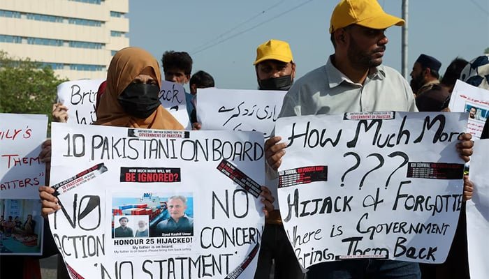 صومالیہ کے ساحل سے بحری قزاقوں کے ہاتھوں اغوا ہونے والے آئل پروڈکٹس ٹینکر آنر 25 کے پاکستانی یرغمال عملے کے ارکان کے اہل خانہ، کراچی میں، 13 مئی 2026 کو، حکومت سے اپنے پیاروں کی بحفاظت واپسی کے لیے فوری ایکشن لینے کے لیے ایک احتجاج کے دوران پلے کارڈز اٹھائے ہوئے ہیں۔ - رائٹرز