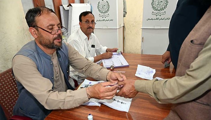 گلگت بلتستان کے عام انتخابات 2026 کے دوران پولنگ اسٹیشن پر ایک انتخابی اہلکار ووٹروں کے انگوٹھے پر سیاہی لگا رہا ہے۔ - اے پی پی