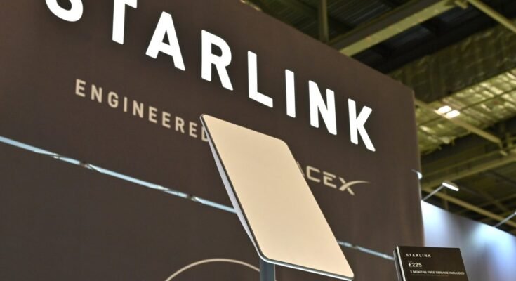 A Starlink terminal in front of a sign that says, "Starlink: Engineered by SpaceX."
