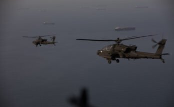 AH-64 Apache helicopters fly above the Strait of Hormuz during a patrol, April 17. Commercial ships are visible on the water below.