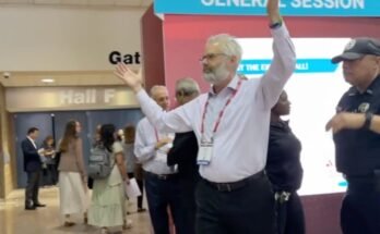 Police escort Dr. Steven Kahn out of a medical conference in New Orleans for handling out copies