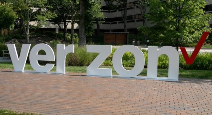 Outside a Verizon corporate building, a sculpture displays Verizon's logo with the letters V-E-R-Z-O-N and a space in the middle where the letter "I" should be.