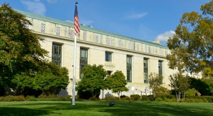 Image of a lawn and a square marble Greek-revival style building.