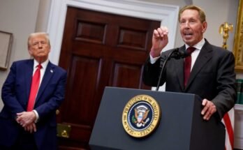 Image of Larry Ellison and President Trump shows Ellison speaking at a podium while Trump stands in the background.