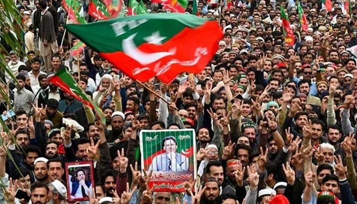 پشاور میں جلسے کے دوران پی ٹی آئی کے حامی پارٹی کے بانی عمران خان کی تصاویر اٹھائے ہوئے ہیں۔ — اے ایف پی/فائل